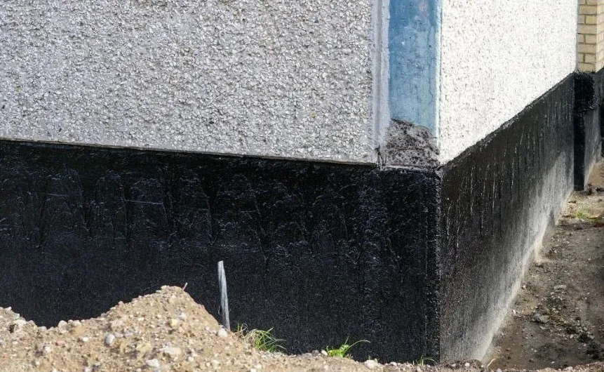 A dark coated foundation wall below a house