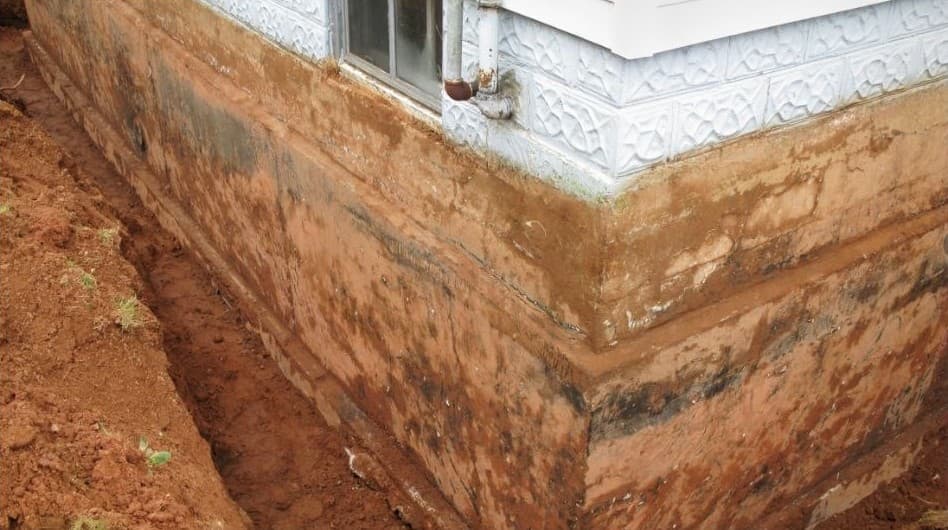 A trench dug along a muddy house wall