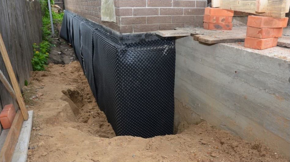 Black dimpled sheet on a dug-out house wall